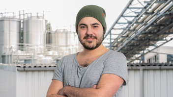 Young employee with beanie in front of factory