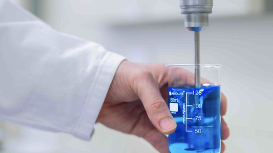 Hand holds container with blue liquid