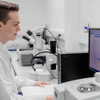 Man in white lab coat in front of computer