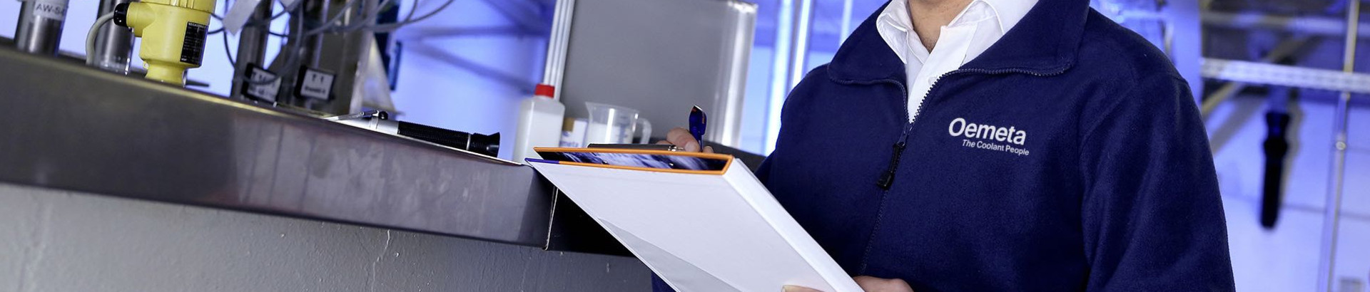 [Translate to United Kingdom (UK):] Man with a blue jacket and a checklist in his hands in a production hall