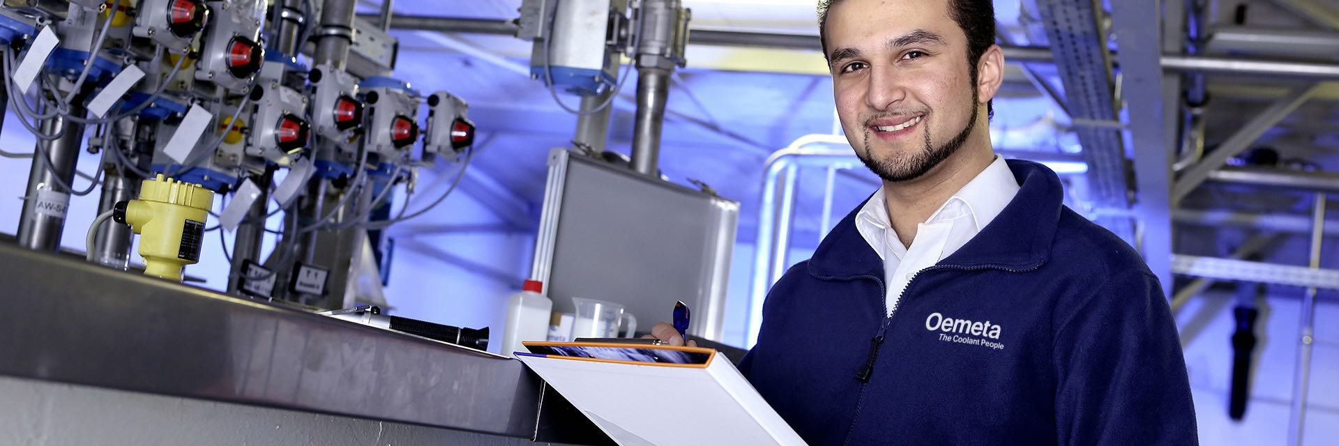 Man with a blue jacket and a checklist in his hands in a production hall