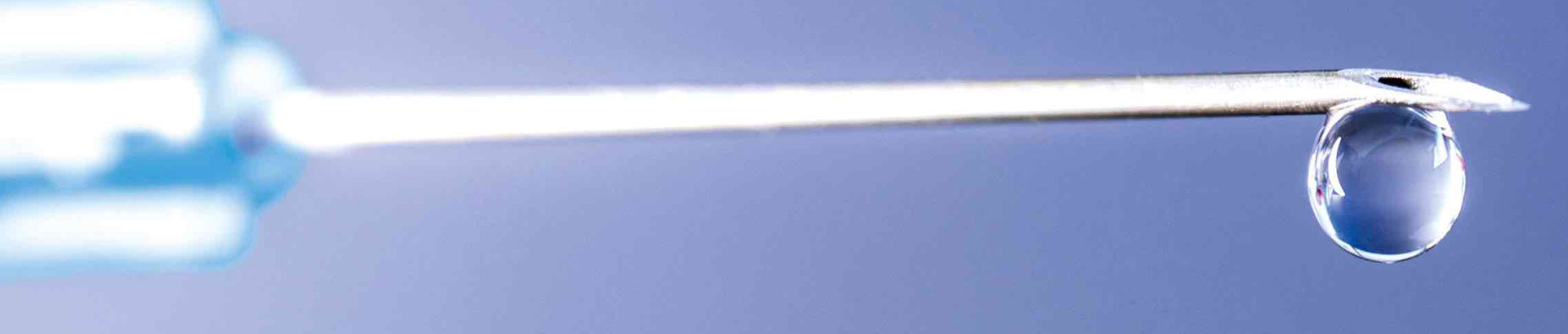 Close-up of a hypodermic needel with a drop hanging from the tip