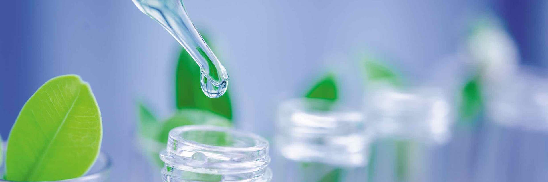 Glass pipettes in front of green plants