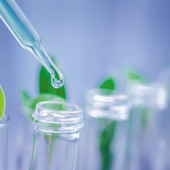 Glass pipettes in front of green plants