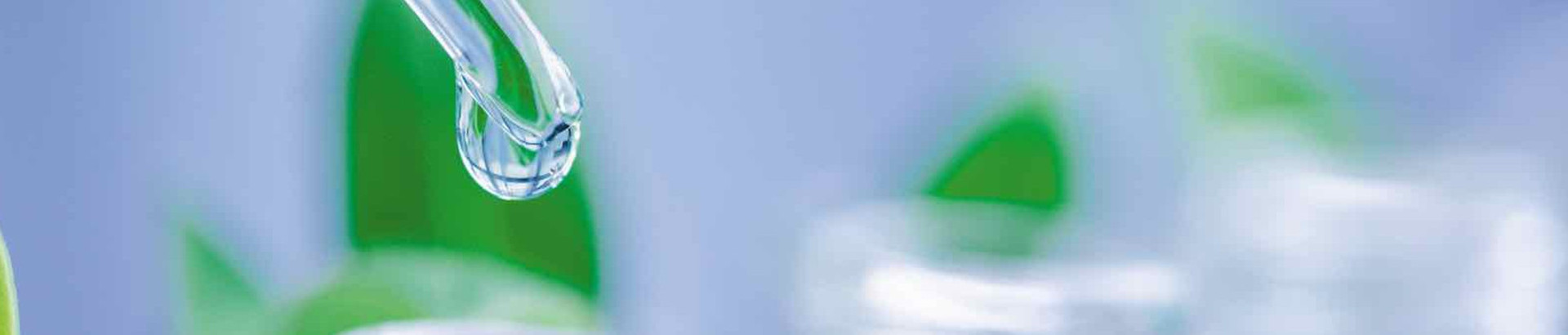 Glass pipettes in front of green plants